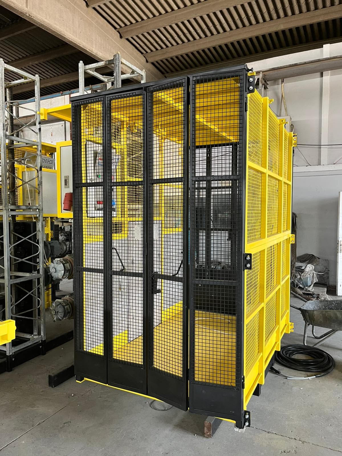 Yellow construction hoist cabin with black safety gates assembled inside the ALPMAKSAN factory
